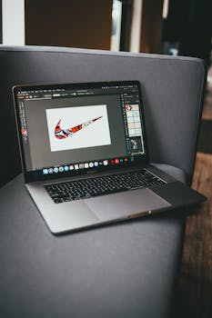 From above of modern netbook with working graphic program located on gray couch in room